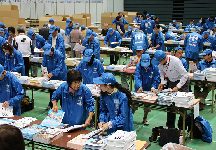 参加者に配布する資料などを袋詰めするボランティア＝富山市総合体育館