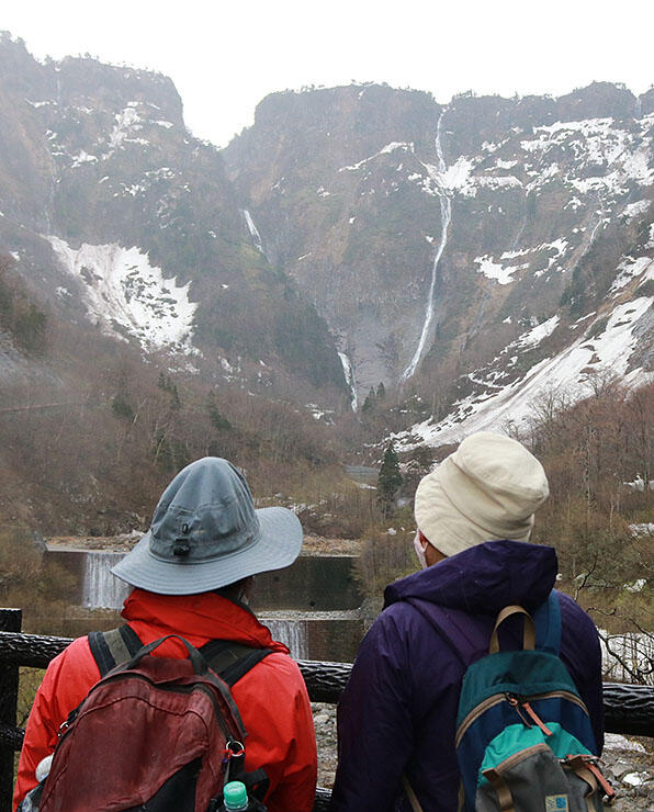 Ｖ字に流れ落ちる称名滝（左）とハンノキ滝を眺める登山者