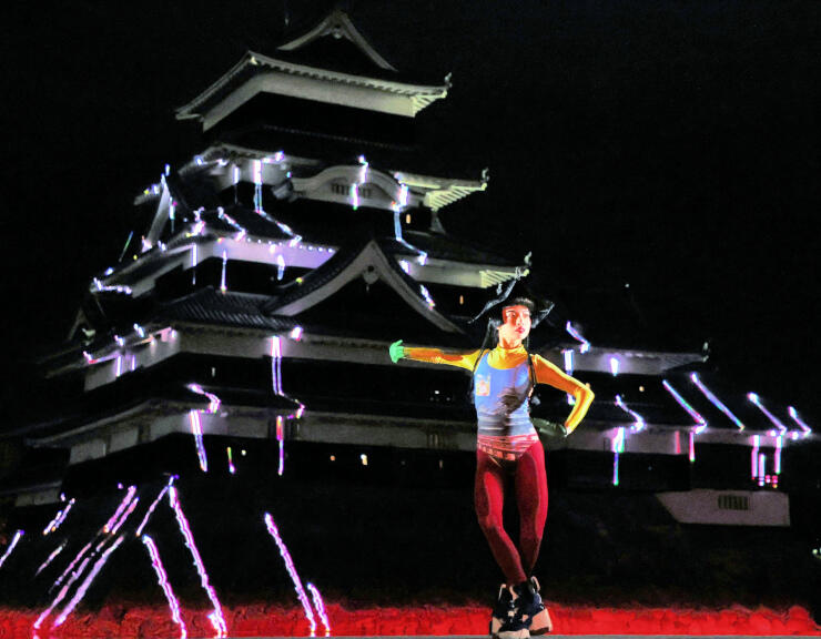 国宝松本城を照らすレーザー光の動きに合わせてダンスを披露するアオイヤマダさん＝１日午後５時５２分、松本市