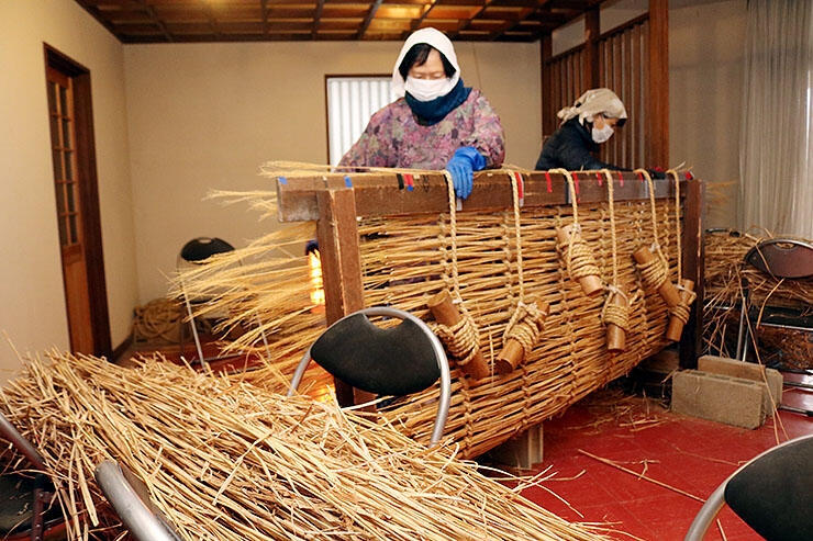 ススキを編んでオオダレを作る女性