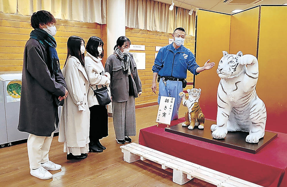 来場者にトラ飾りの特徴を説明する北川さん（右）＝能美市のいしかわ動物園