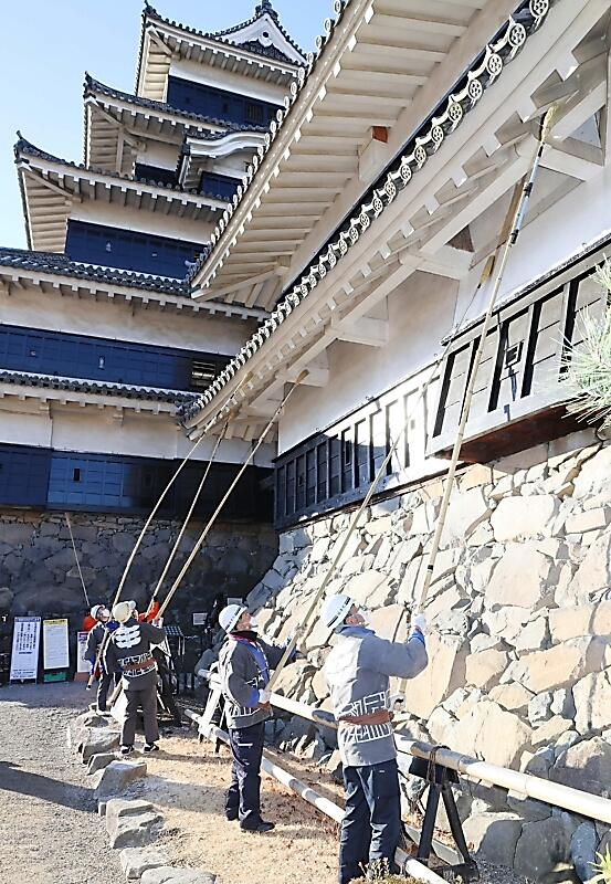 柄の長いほうきでほこりやクモの巣など１年の汚れを落とした松本城のすす払い＝２８日午前８時５６分、松本市