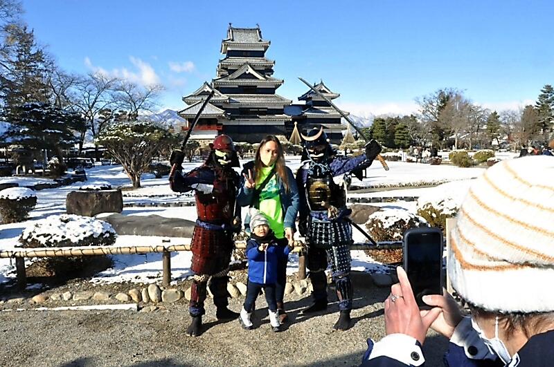 松本城天守を背に記念撮影する人たち
