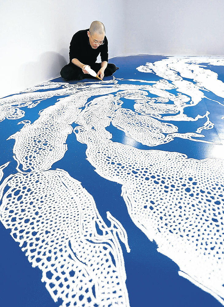 塩を使って渦潮のアートを制作する山本さん＝里見町