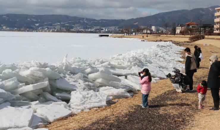 諏訪湖の岸辺に打ち寄せた氷。２４日も見物する人たちがいた＝下諏訪町南高木
