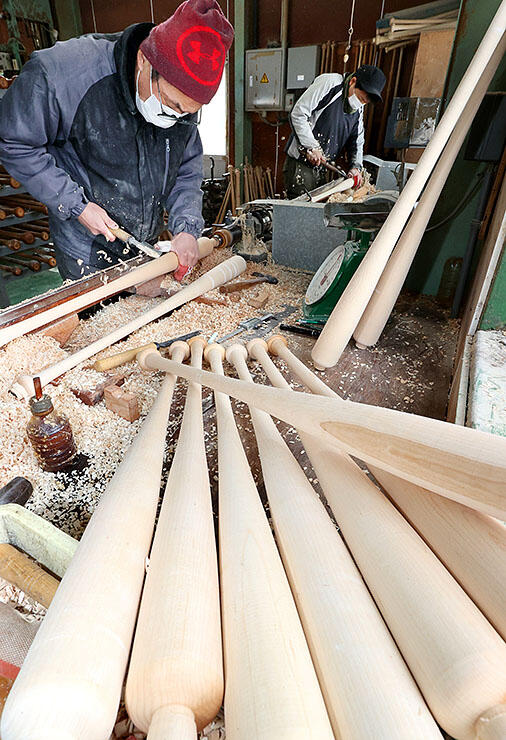 高速回転させた木材を削り、バットを作る職人＝エスオースポーツ工業
