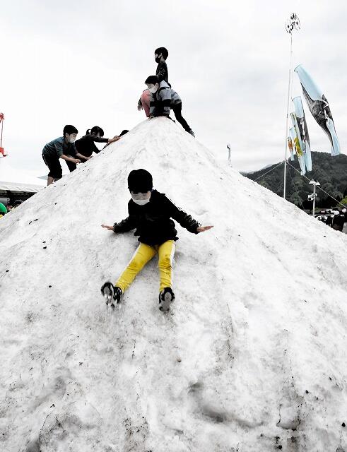 雪山を滑り降りるなどして遊ぶ子どもたち＝４月２９日、勝山市の福井県立恐竜博物館