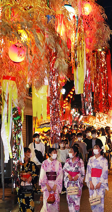 色鮮やかな七夕飾りの下で祭りを楽しむ大勢の人たち＝高岡市戸出町