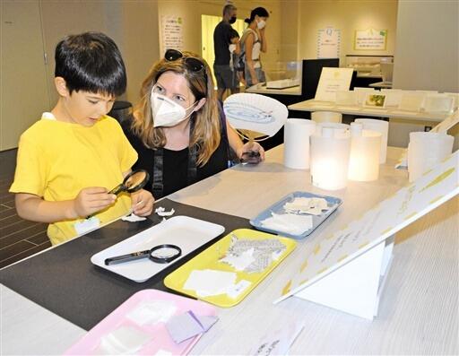 和紙や洋紙の断面を虫眼鏡で観察する子ども＝7月１５日、福井県越前市の紙の文化博物館