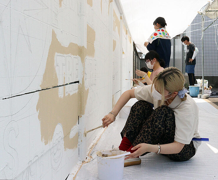 壁にデザインを描く折田さん（手前）ら＝富山競輪場