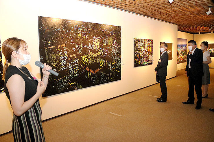 オフィス街の夜景を描いた作品を解説する大村さん（左）＝朝日町ふるさと美術館