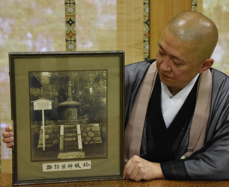 温泉寺で公開する「御鉄塔」の写真を持つ瀧住職