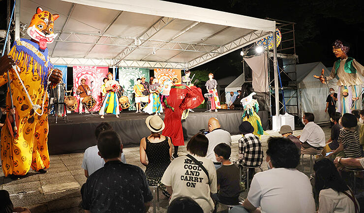 巨大人形と共ににぎやかな演奏が繰り広げられたオープニングステージ＝南砺市福野文化創造センター