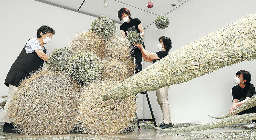 竹の枝や葉を余すことなく使った大作を仕上げる出品者＝金沢２１世紀美術館