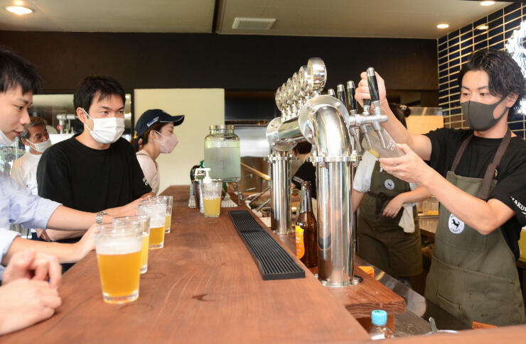 初仕込みのクラフトビールを来場者に振る舞う田口さん（右）