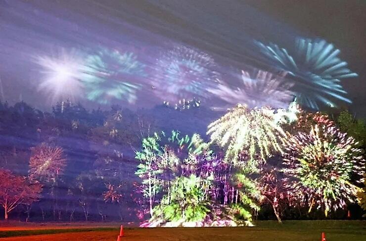 試験点灯で木々に投影される花火。雨粒や霧にも映し出され幻想的な雰囲気になった＝７日午後６時４６分、木曽町日義の木曽文化公園