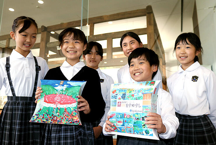 富山の風景や名産を描いた商品パッケージを持つ児童