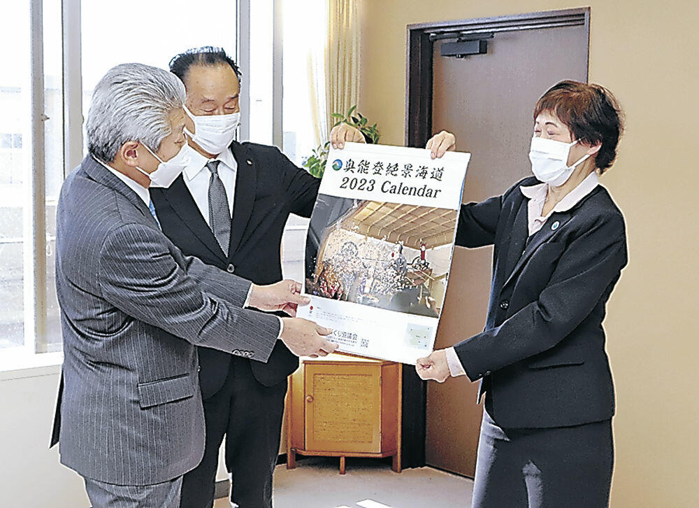 完成したカレンダーを確認する泉谷市長（左）＝珠洲市役所