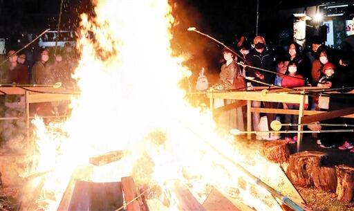 かがり火で生せんべいを焼き、無病息災を願う参拝者＝１１月２０日夜、福井県敦賀市栄新町