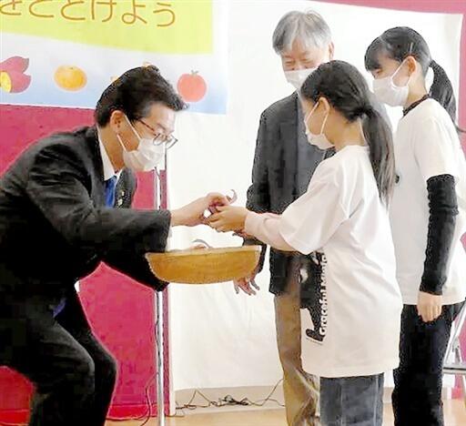 佐々木市長（左）にサツマイモを手渡す友の会の会員＝１２月１０日、福井県鯖江市西山動物園「レッサーパンダのいえ」