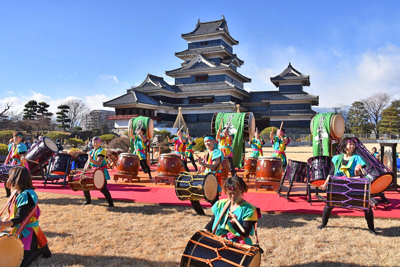 松本城を背に太鼓を打ち鳴らす「国宝松本城古城太鼓」のメンバー