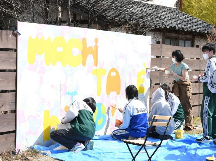 広場に設置された「アートウォール」にペンキで色を塗る高校生ら
