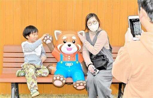 新設されたレッサーパンダのベンチで写真を撮る親子＝３月１７日、福井県鯖江市西山動物園