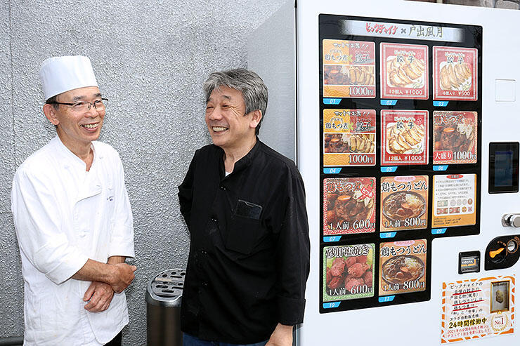 自動販売機の隣で笑顔を見せる（左から）焼田さんと丸岡さん