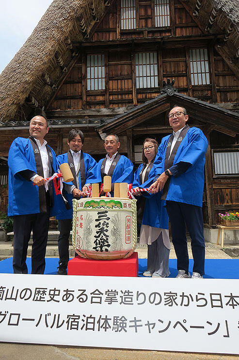 キャンペーン発表を祝い、中島家の前で鏡開きする田邉社長（左）、田中市長（右）と中島さん家族