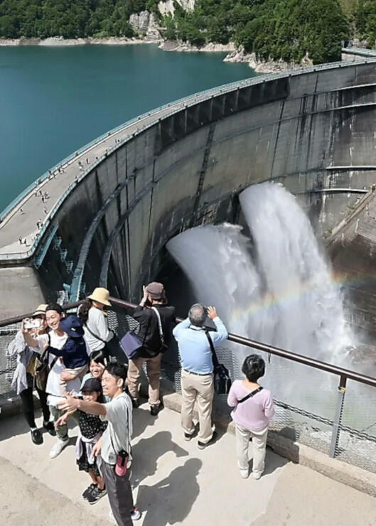 黒部ダムで始まった観光放水。豪快に流れ落ちる水に虹がかかる様子を大勢の観光客が楽しんだ＝２６日午前１０時１１分、富山県立山町