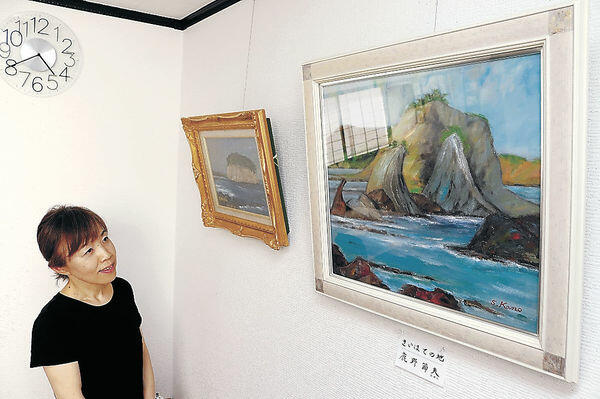 鹿野さんが描いた見附島を眺める中川さん＝金沢市の「ギャラリー＆カフェみやび」