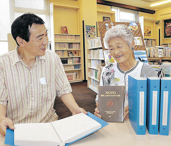加藤さん（左）に点訳本の完成を報告する綿谷さん＝穴水町立図書館