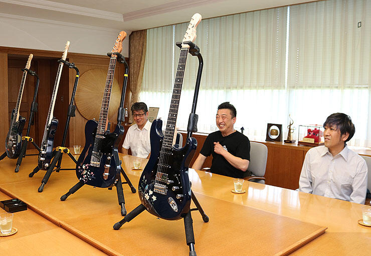 ギターを紹介する（右から）武蔵川さん、太田さん、柴田理事長＝高岡市役所
