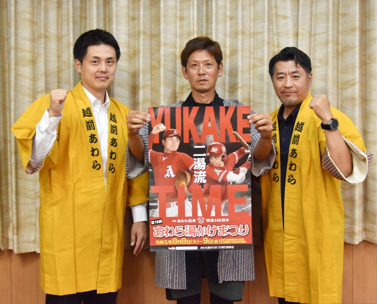 湯かけ祭りのポスターを持つ実行委のメンバー＝７月２７日、福井県あわら市の美松