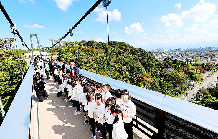 市街地を見渡せるつり橋を楽しそうに通る子どもたち