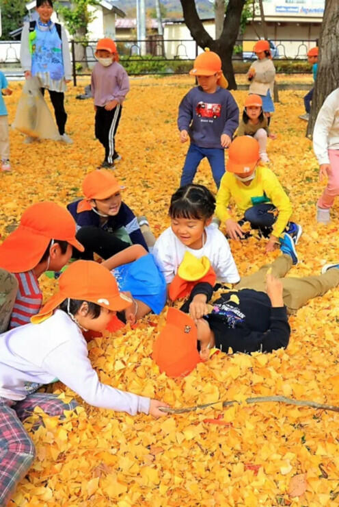 じゅうたんのように広がったイチョウの葉の上で遊ぶ子どもたち＝６日、松本市美須々