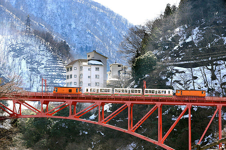 今年２月、雪景色の中で新山彦橋を渡るトロッコ電車