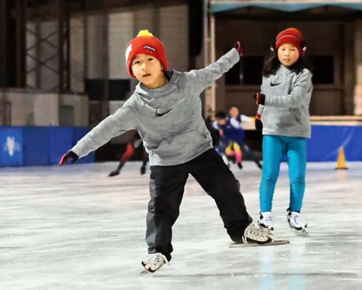 茅野のスケート場でバランスを取りながら滑る子ども