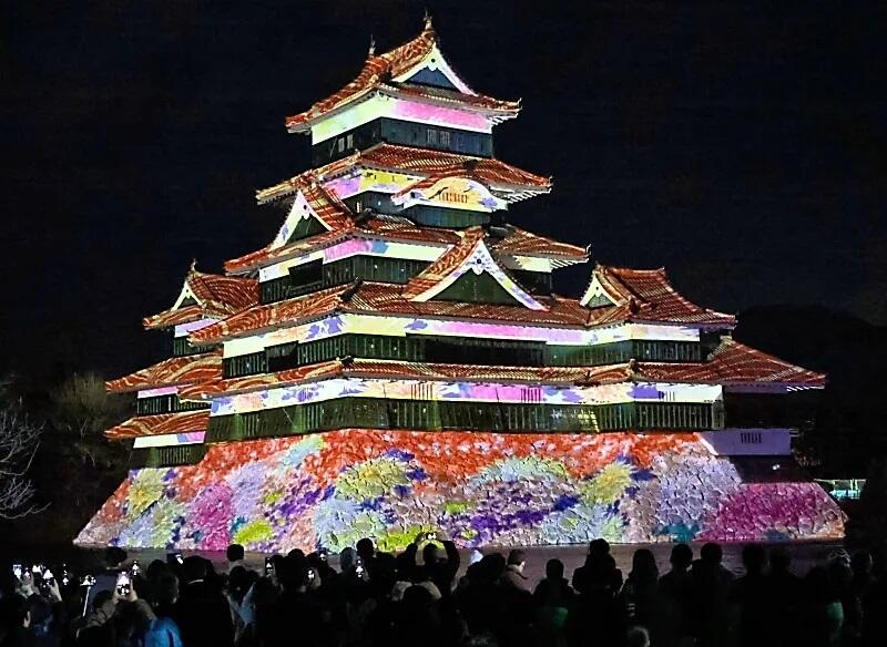 「時代を駆ける歴史絵巻」をテーマにした映像が投影された松本城天守＝１６日午後６時５分、松本市