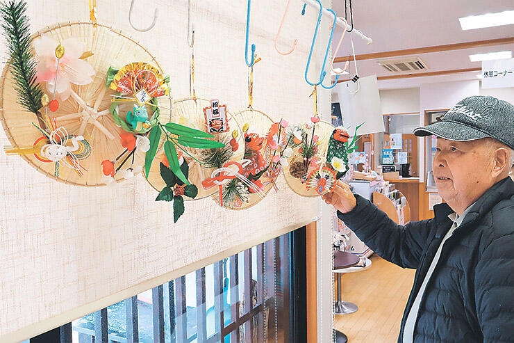 菅笠の正月飾りを手にする買い物客