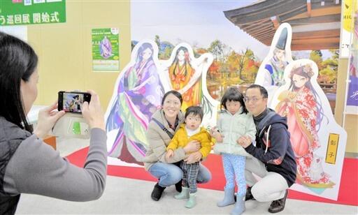 紫式部らのキャラクターパネルの前で記念撮影する家族連れ＝１２月２４日、福井県福井市のエルパ