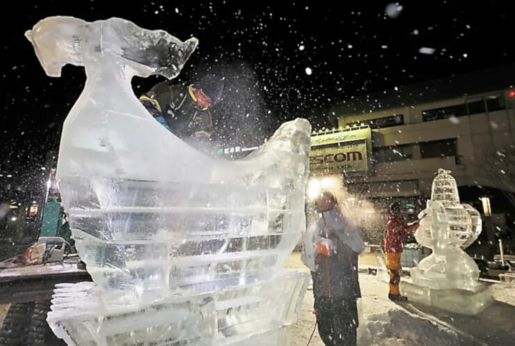 松本駅前で制作が進む氷の彫刻＝２５日午後８時半、松本市