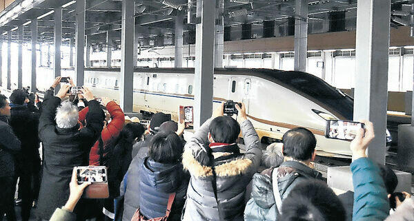 通過する新幹線車両を撮影する参加者＝ＪＲ加賀温泉駅